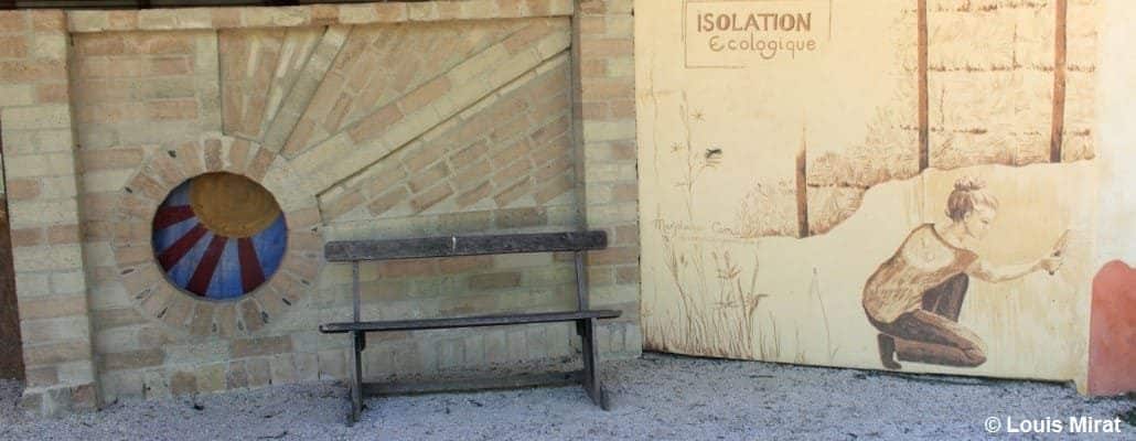 Un banc et un mur avec un graffiti représentant une femme entrain de travailler un mur