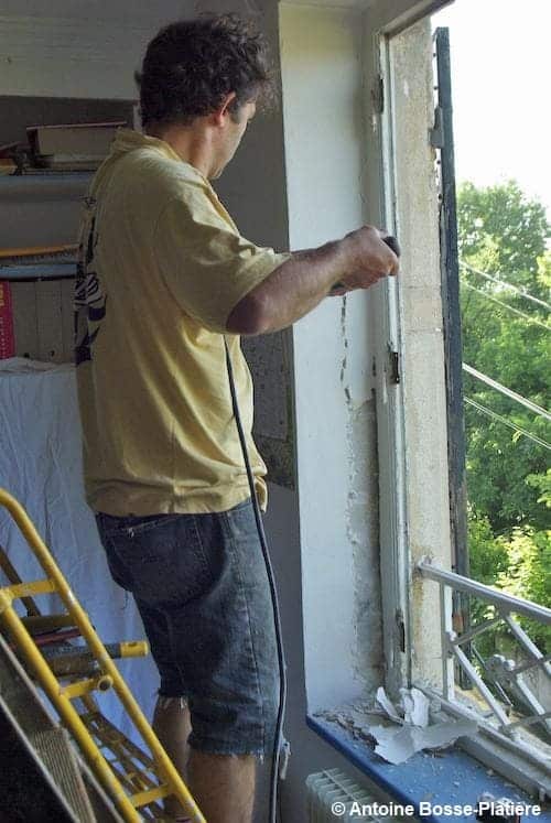 Un homme entrain de bricoler une fenêtre