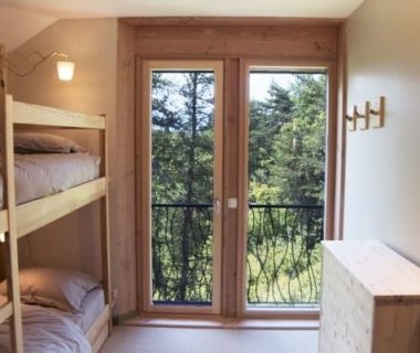 Vue sur un chambre avec deux lits superposés et une grande porte vitrée