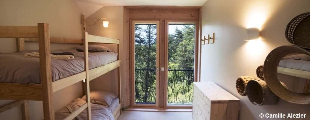 Vue sur un chambre avec deux lits superposés et une grande porte vitrée
