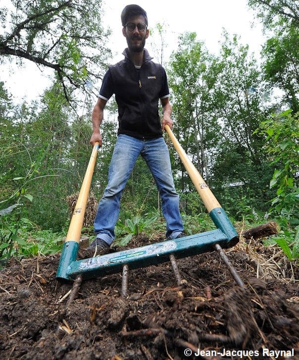 Le jardinier greline avec une fourche à bêcher