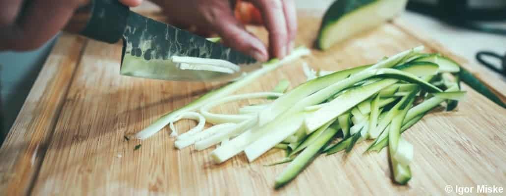 Courgette entrain d'être coupée au couteau en lamelles