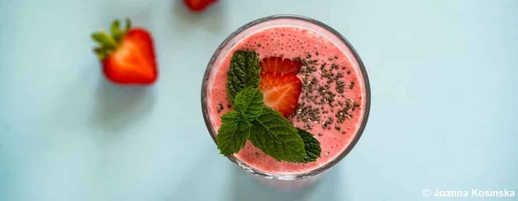 Vue en plongée sur un dessert glacé aux fruits rouges mixés, avec une fraise coupée et de la menthe en décoration