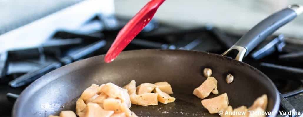 Poêle huilée avec des morceaux de poulet qui cuisent