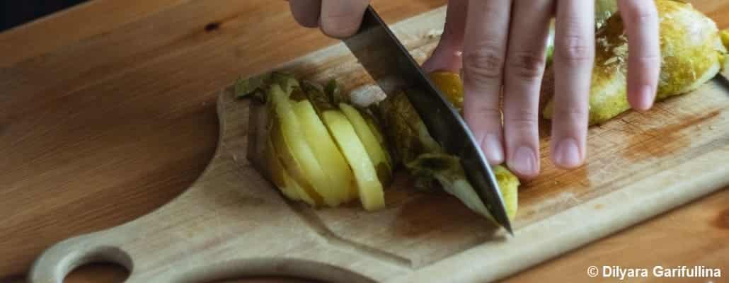 Une main qui coupe des tranches de poires au couteau sur une planche au bois