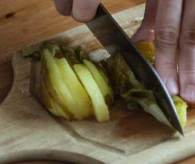 Une main qui coupe des tranches de poires au couteau sur une planche au bois