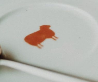 Assiette avec un mouton orange dessiné dessus et une cuillère à côté