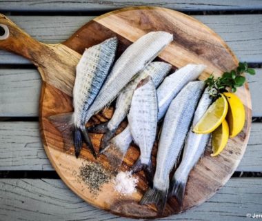 Planche avec plusieurs poissons entiers disposés et du citron