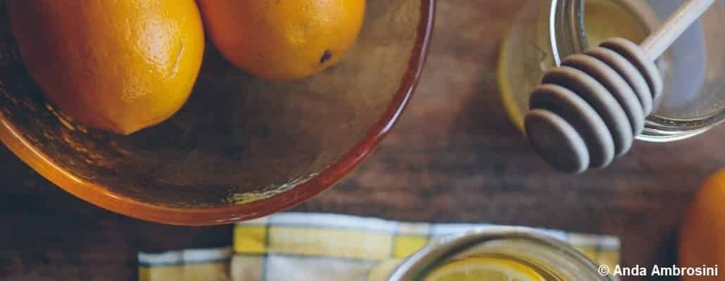 Vue en plongée d'oranges dans un saladier et d'une cuillère à miel