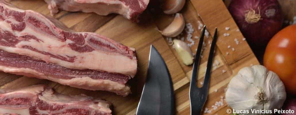 Viande de porc sur une planche en bois, de l'ail et un couteau de cuisine