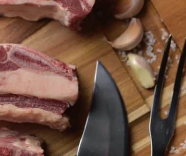 Viande de porc sur une planche en bois, de l'ail et un couteau de cuisine